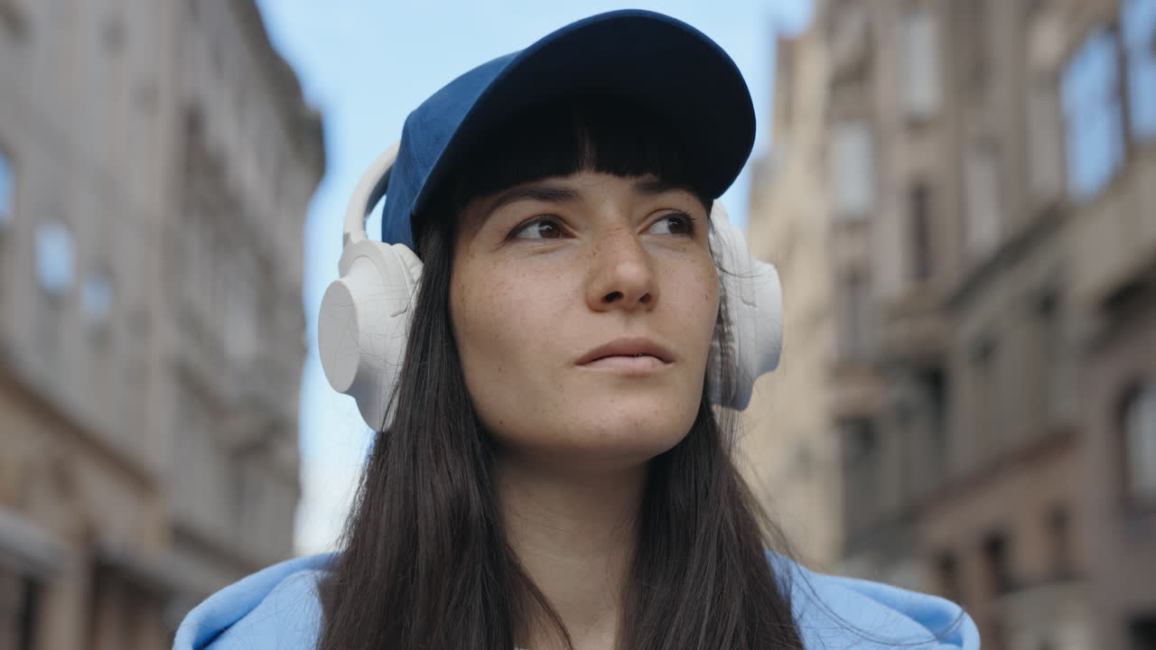 Portrait of a Young Woman with Headphones and Baseball Cap in the City