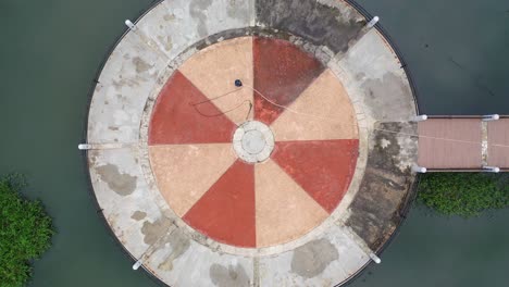 circular platform in a pond with wooden bridge - aerial view