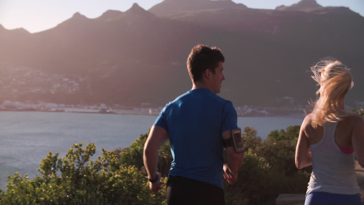 hombre y mujer corriendo por una carretera vacía, cámara lenta, vista trasera