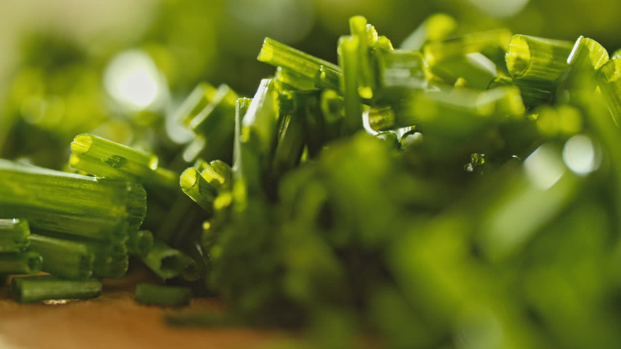 крупный макроснимок свежего измельченного шнитт-лука на деревянной разделочной доске, вращающаяся камера