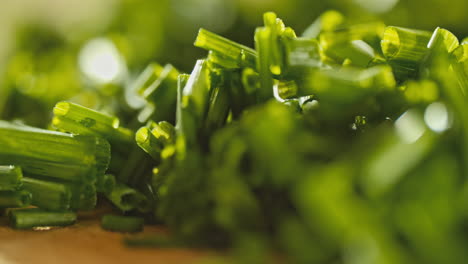 close-macro-shot-of-fresh-chopped-chives-laying-on-a-wooden-cutting-board,-rotating-camera