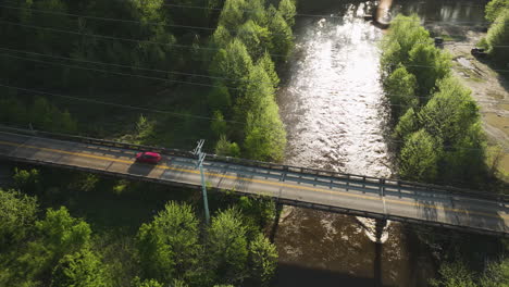 Sunlight glistens on Wolf River with a car crossing the bridge in Collierville, Tennessee, aerial shot