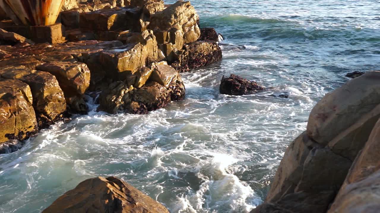 Onde che si infrangono sugli scogli in una giornata di sole a Plettenberg Bay, Sudafrica