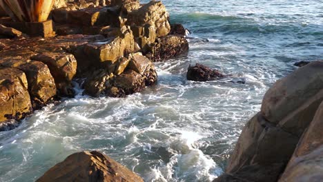 Olas-Rompiendo-En-Las-Rocas-En-Un-Día-Soleado-En-Plettenberg-Bay,-Sudáfrica