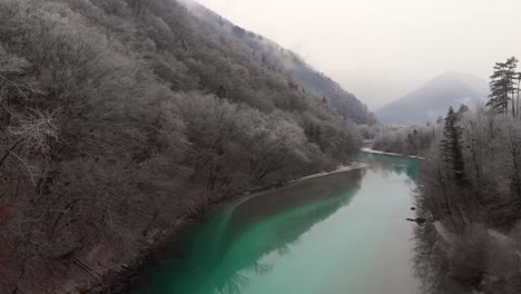 el dron vuela a baja altura sobre el río esmeralda limpio en la fría y brumosa mañana de invierno