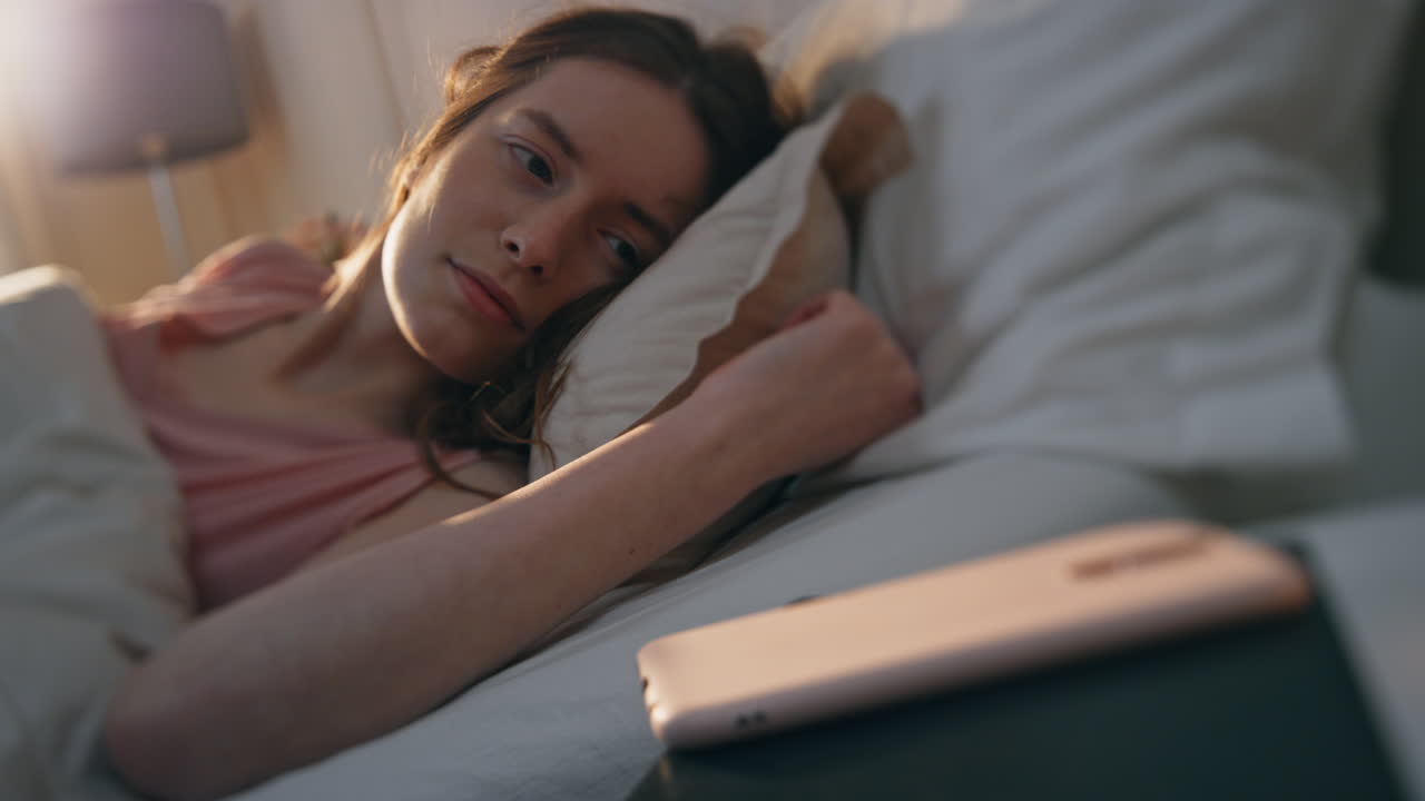 mujer tranquila de primer plano despertando temprano en la mañana. sonriente niña somnolienta llegar móvil
