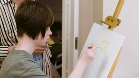 young girl with down syndrome paints a sun on a canvas