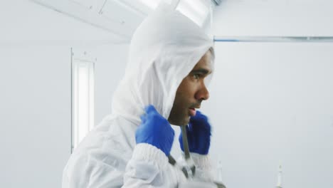 Mixed-race-male-car-mechanic-putting-protective-clothes-on-and-looking-at-camera