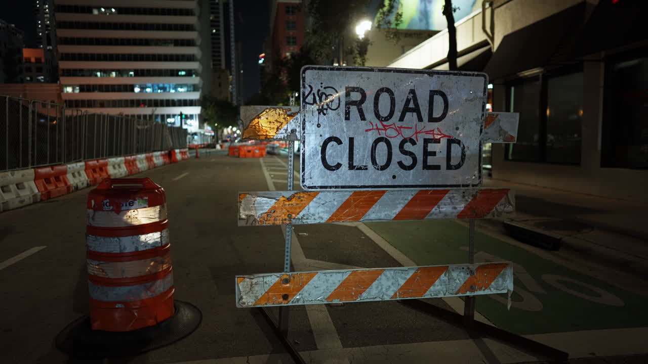 Scena di strada notturna chiusa con barricata e cartello di strada chiusa in una via della città. L'area urbana in costruzione mostra barriere di sicurezza per interruzione del traffico e lavori notturni alle infrastrutture.