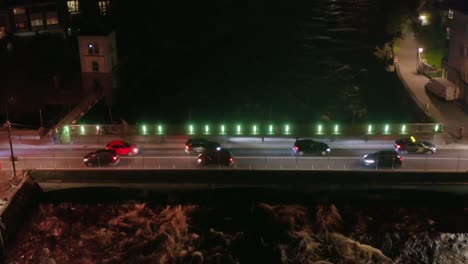 Bridge-over-a-flowing-river-with-traffic-at-nighttime