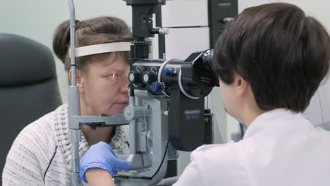 woman doctor is viewing through ophthalmoscope in eyes of patient in ophthalmologic clinic. professional inspection of vision