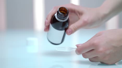 woman hand pouring medicine syrup. liquid drug dosage. flu treatment