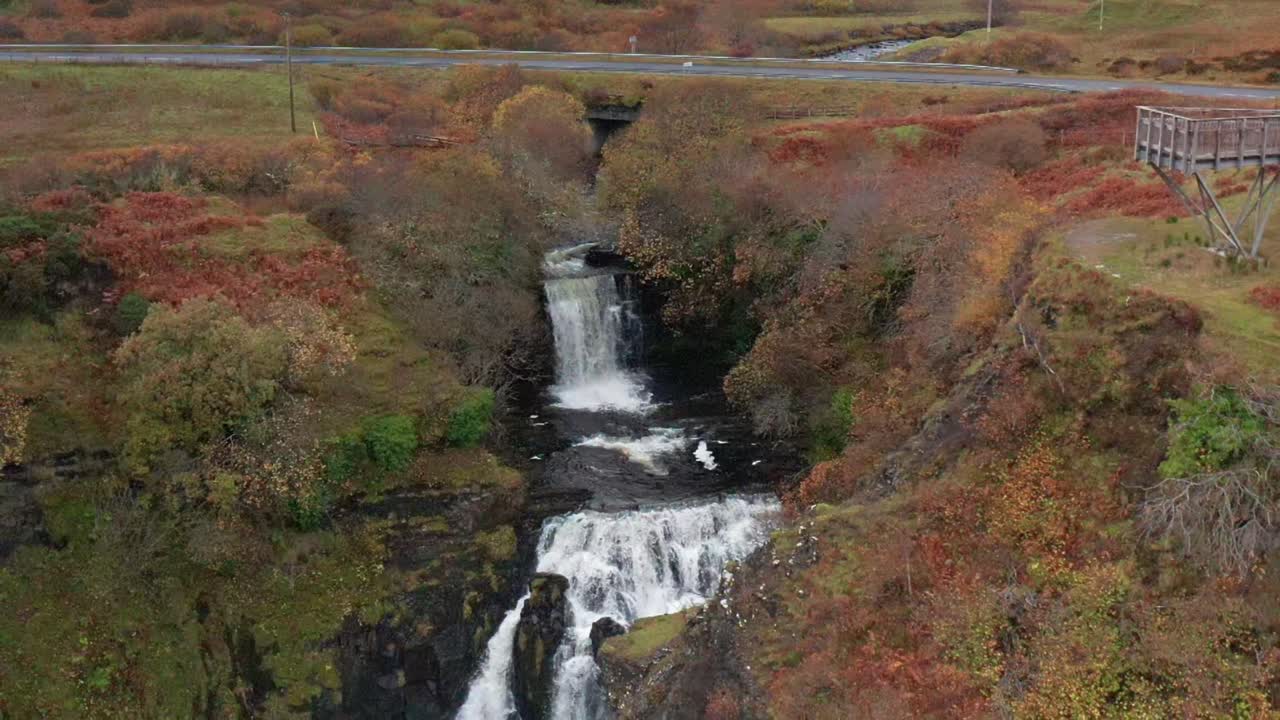 vuelo aéreo de aviones no tripulados en cámara lenta sobre la cascada de lealt fall en skye, escocia, otoño