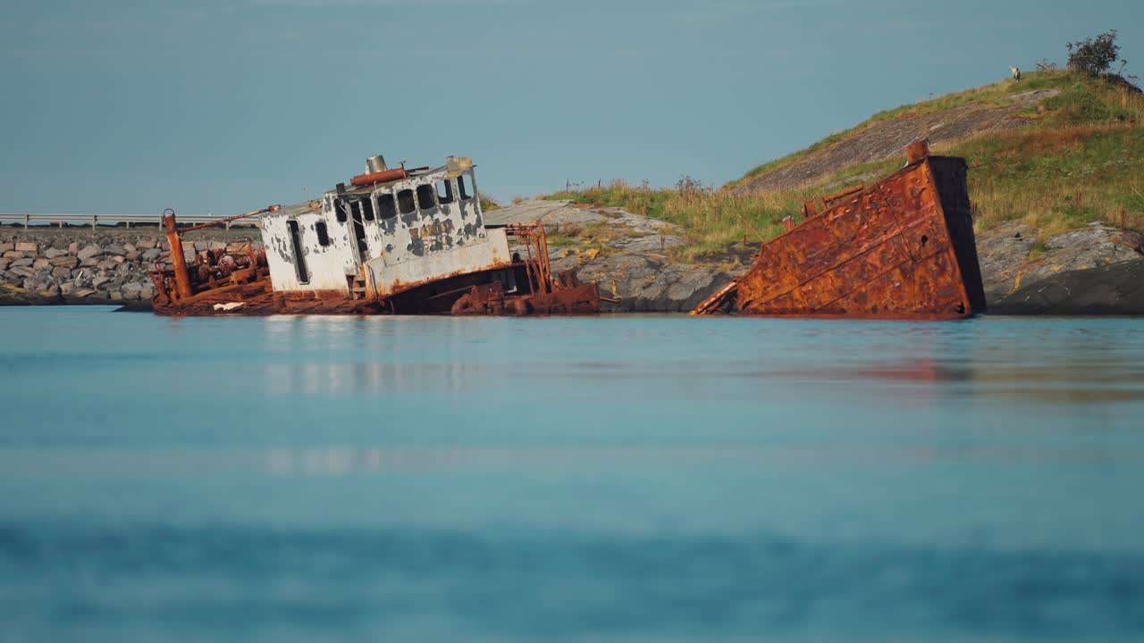 un naufragio abandonado y oxidado descansando en la orilla, rodeado de aguas azules tranquilas
