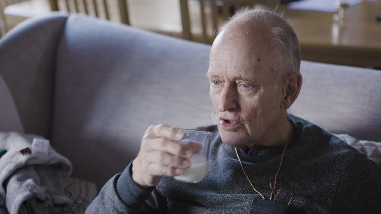 Elderly man resting on couch and drinking milk