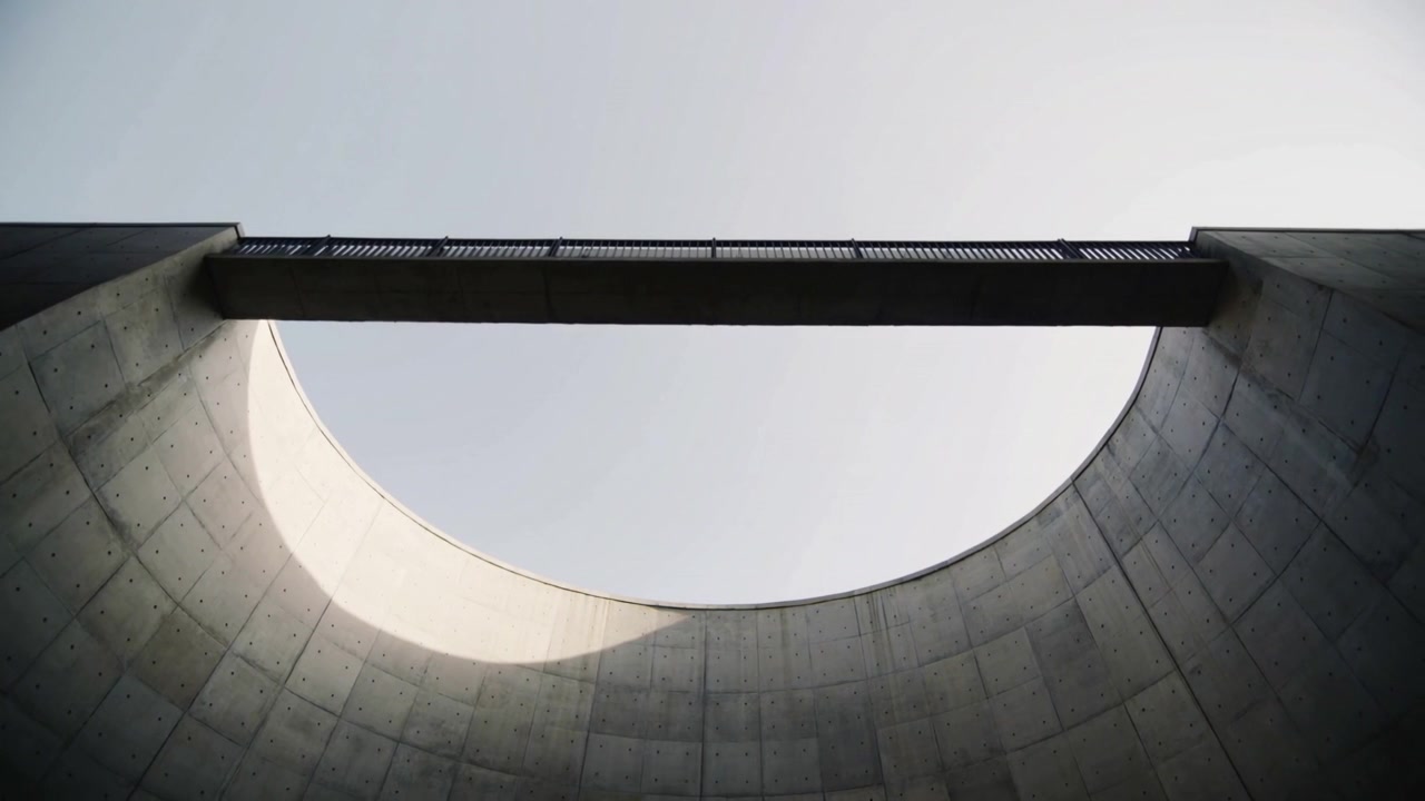 L'arco del sole che si sposta in senso orario lungo un pozzo di cemento, mostrando un oculo e un ponte.