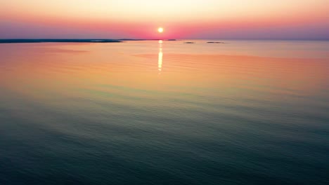 colorful ocean sunrise in saco, maine with bright colors reflecting off calm rippling sea waves along the new england atlantic coastline