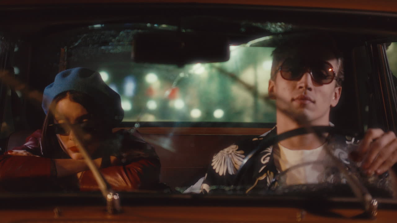 Man Driving Vintage Car with Girlfriend Leaning on Front Seat at Night