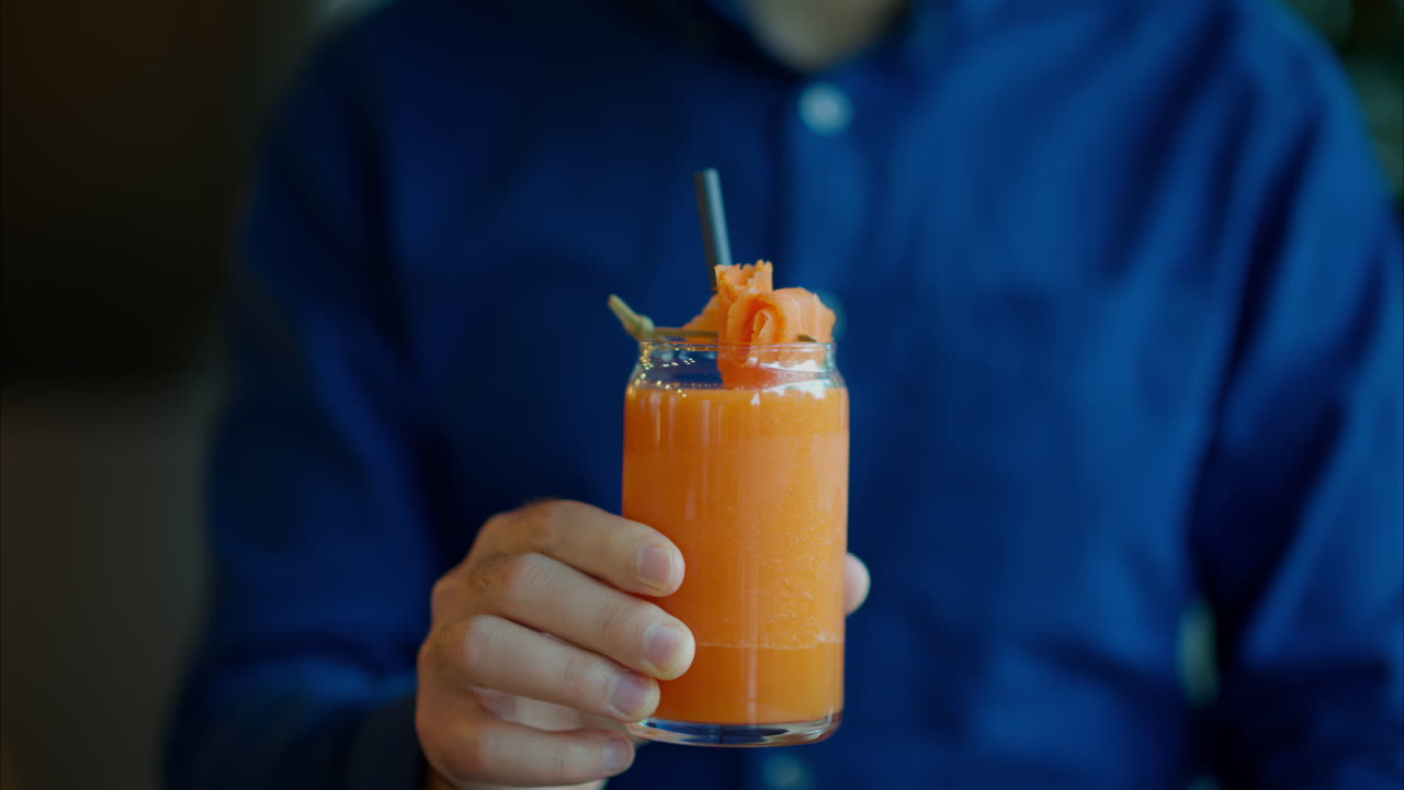 Uomo che beve succo di carota con una cannuccia in un ristorante