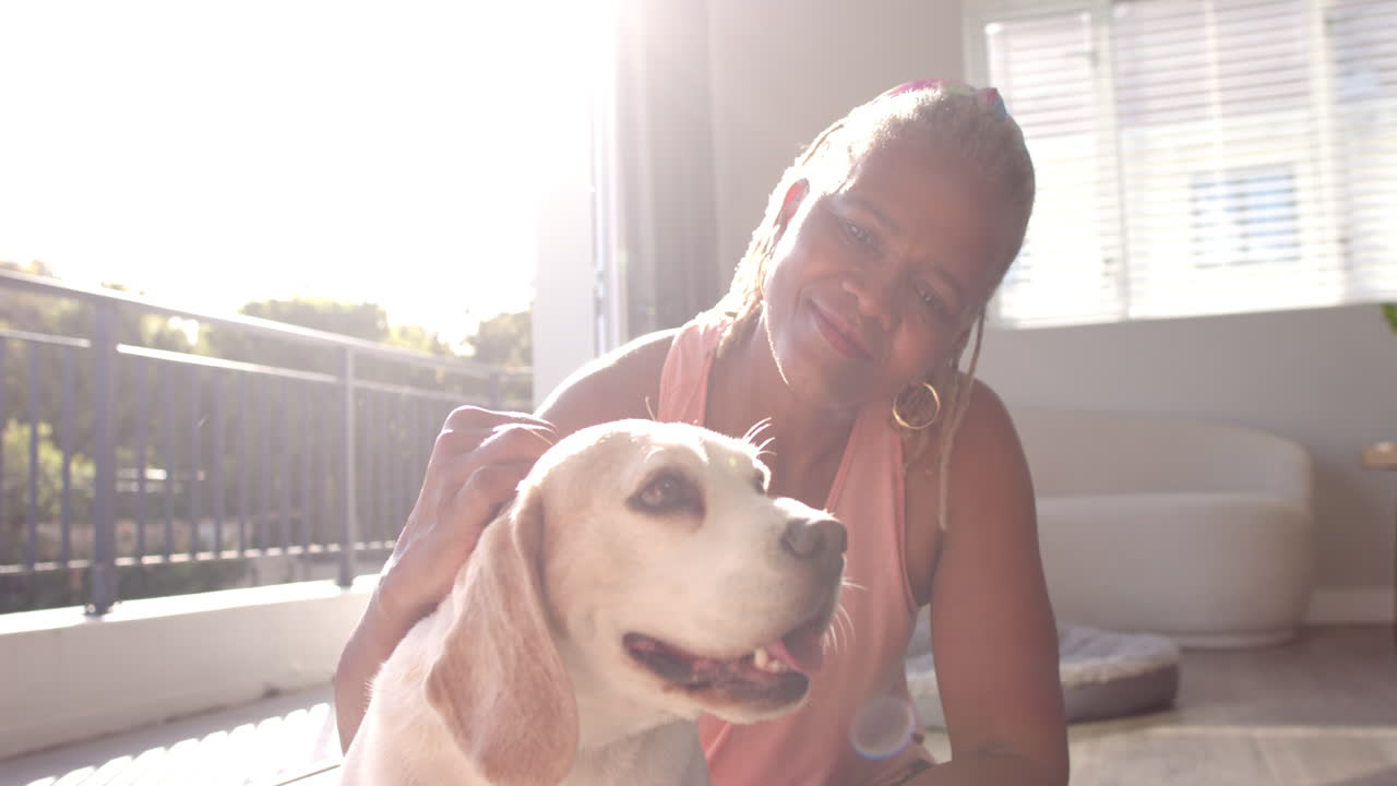 A senior African American woman is petting her dog at home