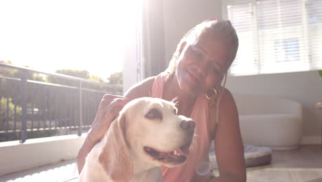 a senior african american woman is petting her dog at home
