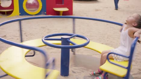 little girl spinning merry go round carousel amusement park playground summer day