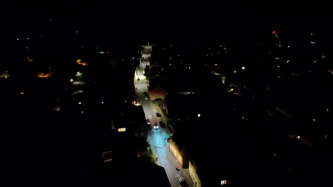 Driving cars with headlights on illuminated streets of American town at night. Aerial flyover shot. Lighting lantern along hilly road. Housing area and neighborhood in suburb of USA