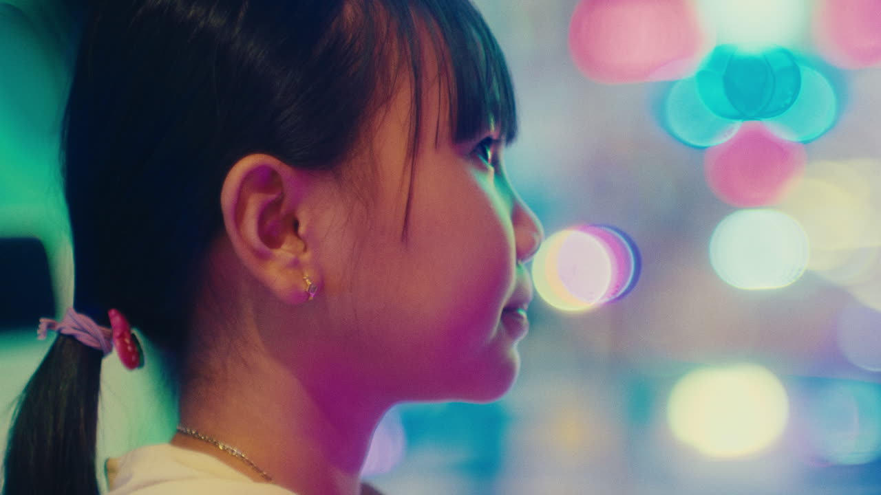 화려한 빛으로 흐릿한 배경 보케 효과와 함께 비디오 게임을 하는 동안 어린 귀여운 아시아 소녀 초상화