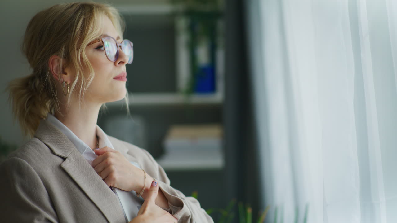 una mujer de negocios feliz mira por la ventana en la oficina.