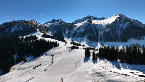 The-drone-is-flying-over-ski-slopes-where-people-are-skiing,-ski-gondola,-restaurant-and-mountains-in-the-background-in-Austria-Aerial-Footage-4K