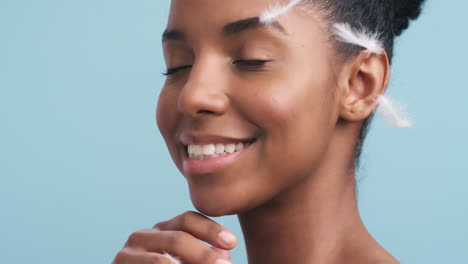 Happy-black-woman-blowing-soft-feathers-against