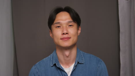 young man in photo booth having fun posing for portrait and pulling funny faces shot in real time