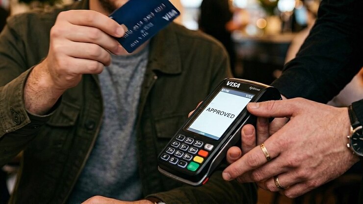 Customer Making Contactless Payment with Credit Card at Point of Sale Terminal