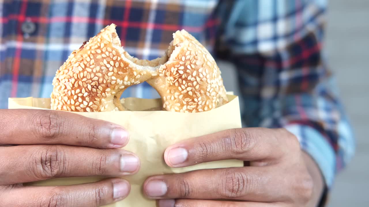 persona sosteniendo un bagel en una bolsa de papel