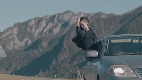 lady with long dark hair sits on car window and enjoys life