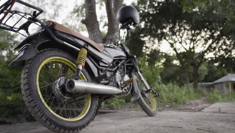 Slider-right-of-motorcycle-parked-with-helmet-on-handlebars