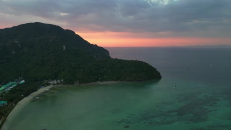 aerial view of a tropical thailand island showing resorts and boats at sunset with a dramatic sky