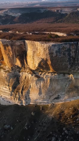 aerial view of a dramatic cliff face with forest below