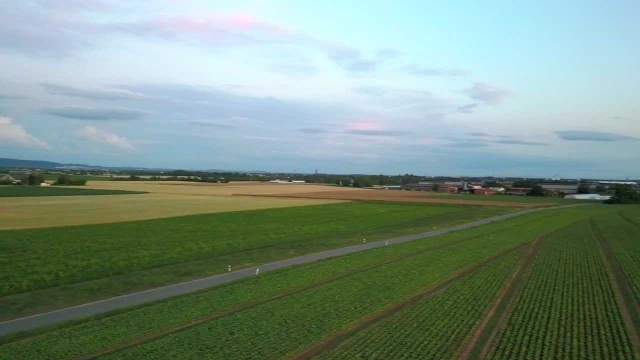 Panning right over beautiful mountainous landscape with crop fields and roads during sunset, Germany