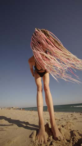 woman on the beach with pink braids
