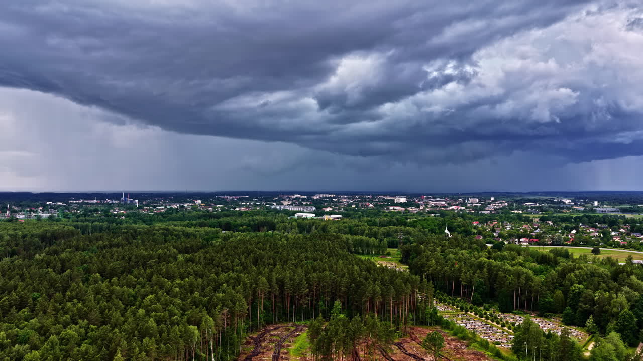 Wide aerial of farmland and villages under dramatic storm cloudy sky in Latvia