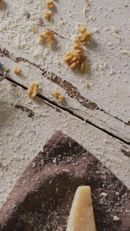 video of cheese grater, grated cheese and nuts on rustic painted wooden table top with copy space