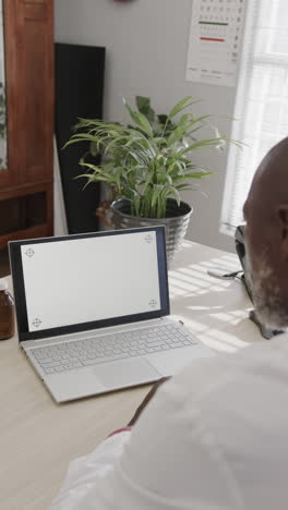 vertical video of african american male doctor using laptop with copy space, slow motion