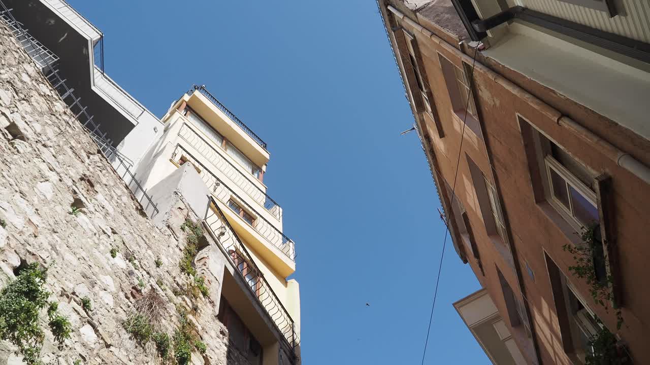 vista hacia arriba de una calle estrecha con viejos edificios y paredes de piedra