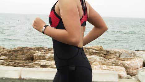 cropped shot of female triathlete jogging along promenade