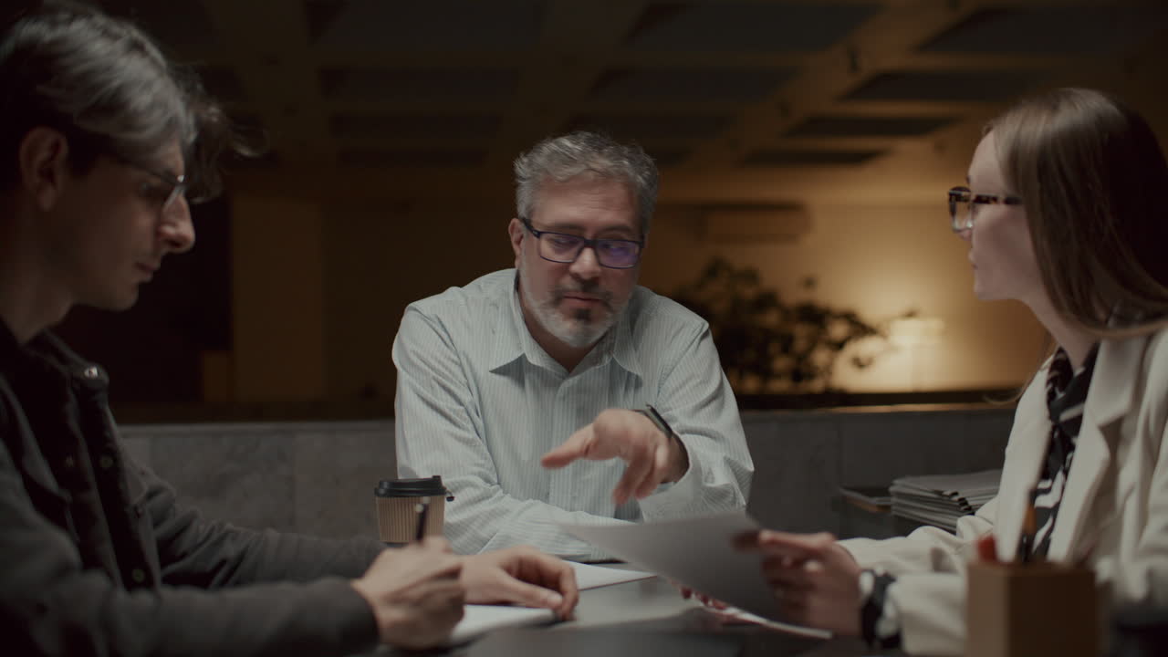 Senior Businessman Leading Late Night Meeting with Colleagues in Office