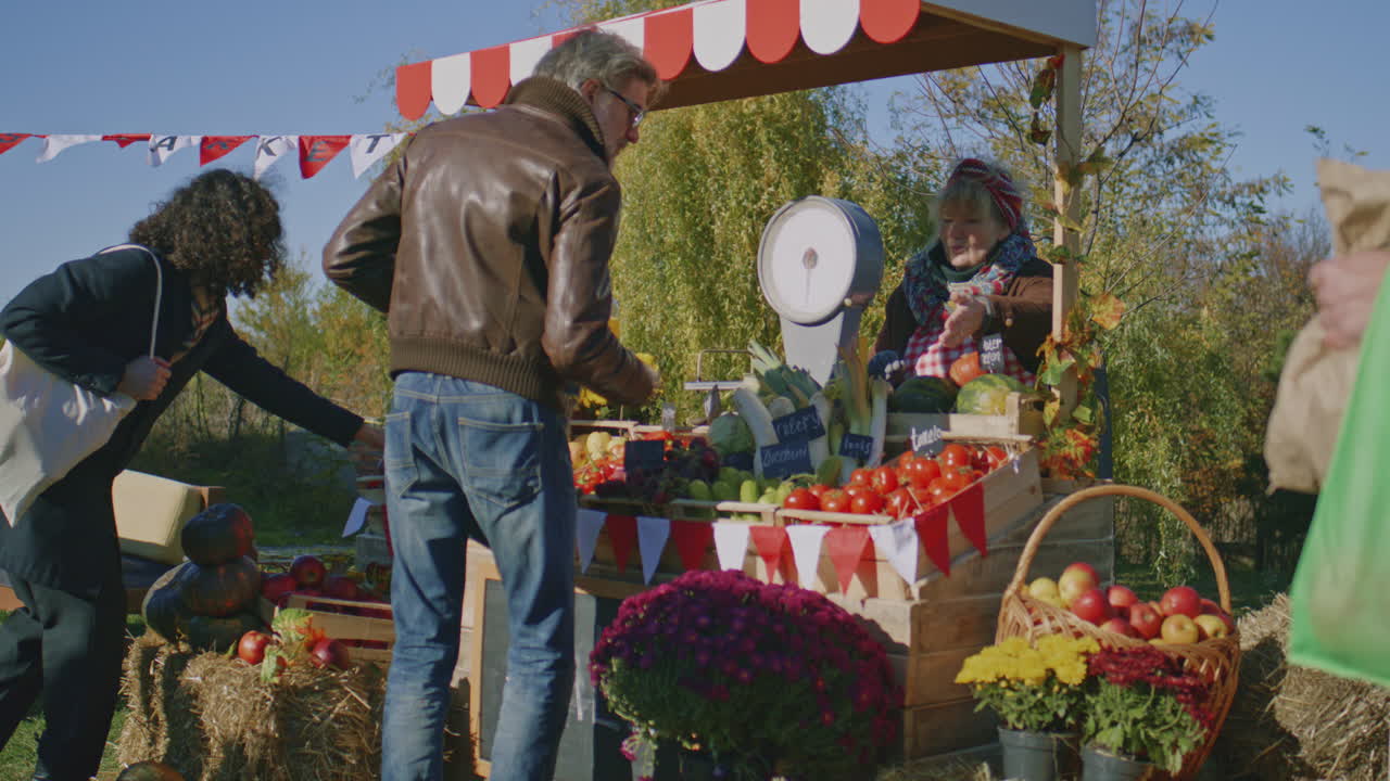 Mature Man in Sunglasses Choose Fresh Vegetables Mature Man in Sunglasses Choose Fresh Vegetables or Fruits and Weight them Holder of Sales Point Offers own Products Shopping at Local Farmers Market on Weekend Vegetarian and Organic Food