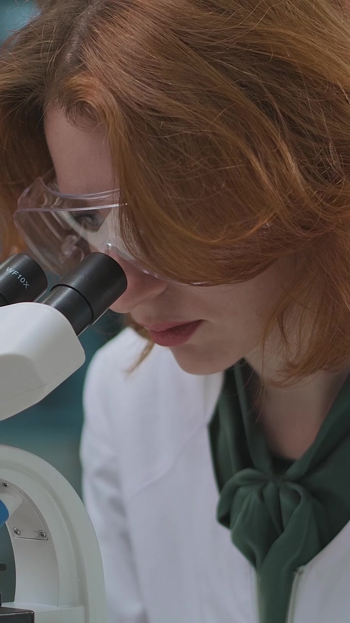 Focused Woman Scientist Examining Sample Under Microscope