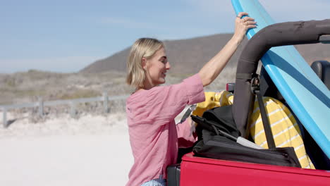 une jeune femme caucasienne emballe une voiture pour un voyage à la plage sur un voyage en voiture avec un espace de copie