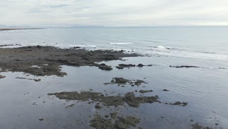 Aerial-view-of-calm-ocean,-slow-waves,-cloudy-day-at-Ytri-Tunga,-Snaefellsnes